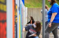 Glenville State College students add to the colorful bookshelf mural behind the Robert F. Kidd Library (GSC Photo/Kristen Cosner)