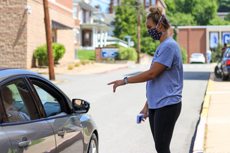 Head Glenville State College Women’s Basketball Coach Kim Stephens greets a driver and passenger entering the main campus as they pause for screening