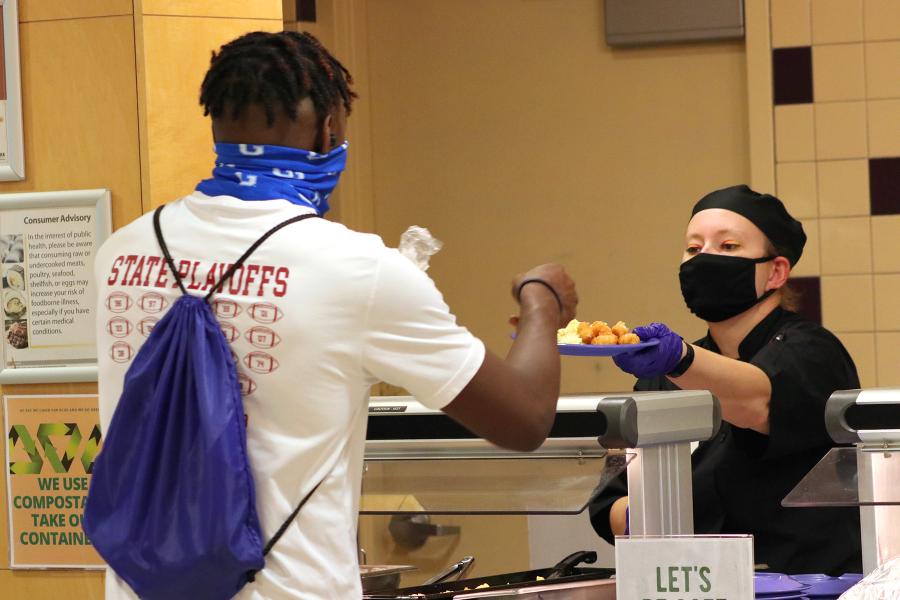Between orientation sessions, a new student pauses for brunch served here by Food Service Worker Lindsay Forren