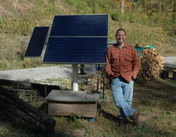 John by the solar panels that power his home. 