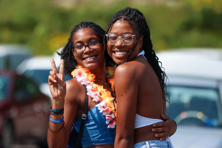 Two minority students hugging, one giving the peace sign