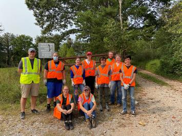 Forestry Club members posing on the side of a dirt road, wearing safety vests
