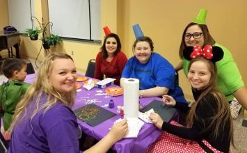 SRIG members sitting around a table with local children