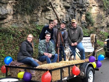 Club members riding a float with balloons and a tripod