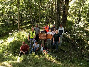Forestry Club members posing in front of a sign for Skip Johnson Trail and Triplets Run Trail