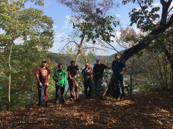 Forestry Club members standing in some woods, holding various tools