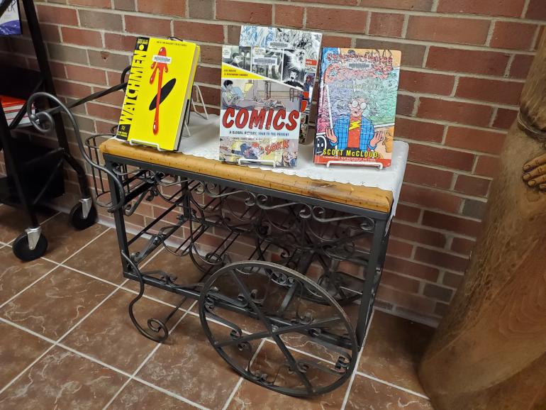 Books and comicbooks on a stand in the library.