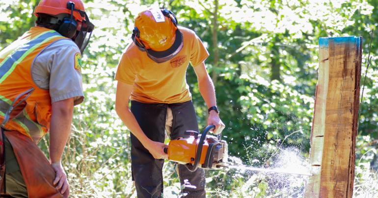 Chainsaw Workshop West Virginia Division of Forestry employee Johnny King (left) watches as Glenville State College student Adem Hupp practices boring into a tree during the Timber Felling and Chainsaw Safety Workshop. (GSC Photo/Dustin Crutchfield)