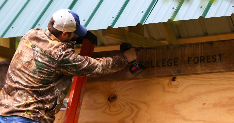 Ethan Carr attaches a sign marking the entrance to the Glenville State College Forest. Ethan Carr attaches a sign marking the entrance to the Glenville State College Forest. (GSC Photo/Dustin Crutchfield)