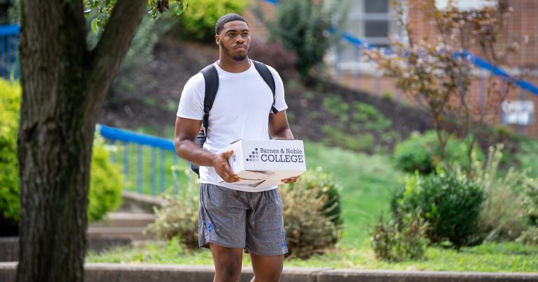 A Glenville State University student carries a box of books from the Barnes and Noble Pioneer Campus Store. (GSU Photo/Kristen Cosner)