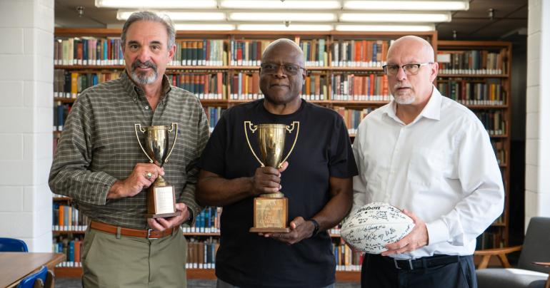 (l-r) Rex Repass, Rick Hurt, and Glenville State University Athletic Director Jesse Skiles hold a few of the items donated to the Glenville State Archives that previously belonged to Coach Frank Vincent. (GSU Photo/Kristen Cosner)