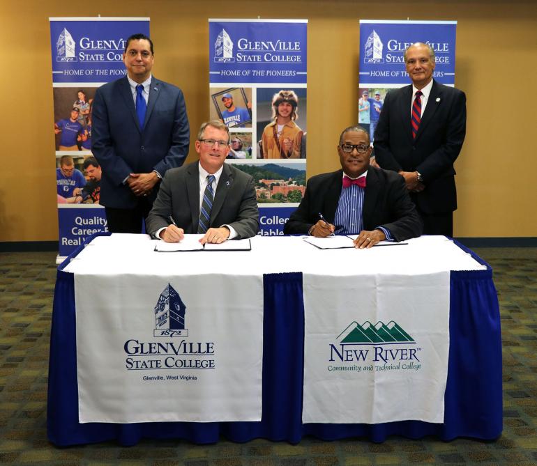 (seated) Glenville State College President Dr. Tracy Pellet and New River Community and Technical College President Dr. L. Marshall Washington sign agreement documents between the two institutions; (standing) GSC's Vice President for Academic Affairs Dr. Gary Morris and New River CTC Vice President for Academic Affairs Dr. Richard B. Pagan