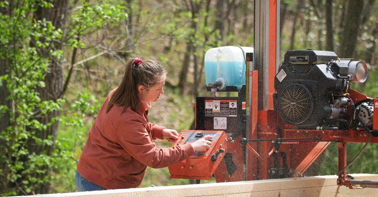 Glenville State College student Gabrielle Dean cuts a log down into boards using the College’s portable Wood-Mizer bandsaw. (GSC Photo/Kristen Cosner)