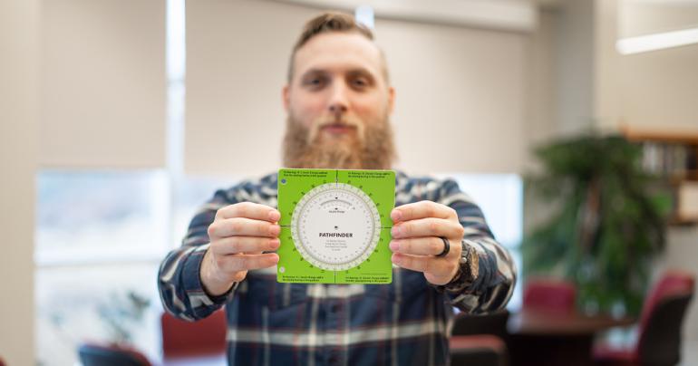 Glenville State University Lecturer of Land Surveying, Jacob Petry, holds a copy of his invention – the Pathfinder: Directional Conversion Wheel. (GSU Photo/Kristen Cosner)