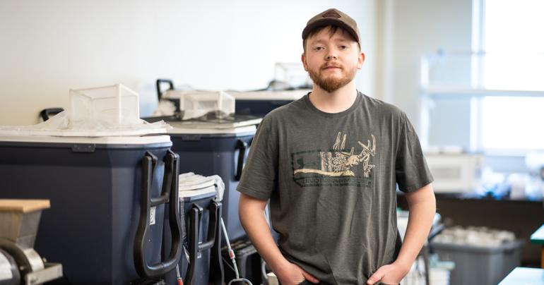 Glenville State University student Jared Bishop stands near his experiment setup inside the Department of Land Resources Environmental Science lab. (GSU Photo/Kristen Cosner)