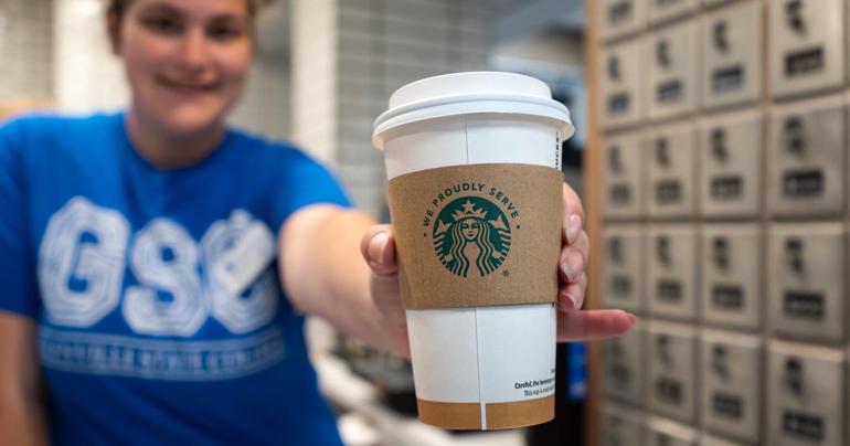 Glenville State University coffee shop employee Caroline Tinnel holds out a We Proudly Serve Starbucks cup. (GSU Photo/Kristen Cosner)