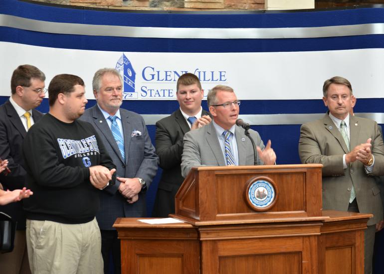 With incoming Glenville State College President Dr. Tracy Pellett at the podium, (l-r) Delegate Roger Hanshaw (R-Clay), GSC student Justin Woods, Board of Governors Chair Greg Smith, Student Government Association President Cameron Woods, and Delegate Brent Boggs (D-Braxton) listen to his announcement on Thursday morning