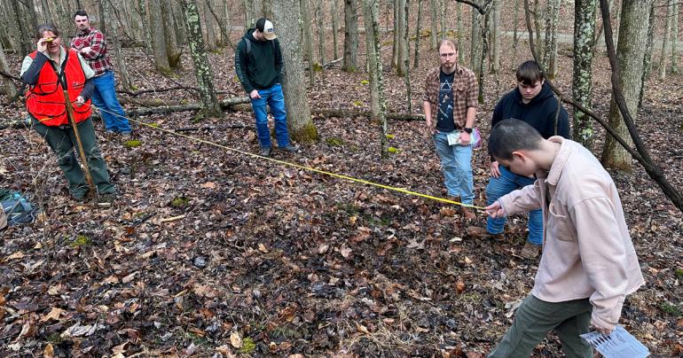 U.S. Forest Service Forester Karen Kubly (left, in orange vest) and Glenville State University student Chloe Richardson (right, holding measuring tape) take field observations with other students in the background. (Courtesy photo)