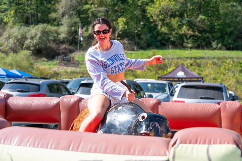 A student rides a mechanical bull