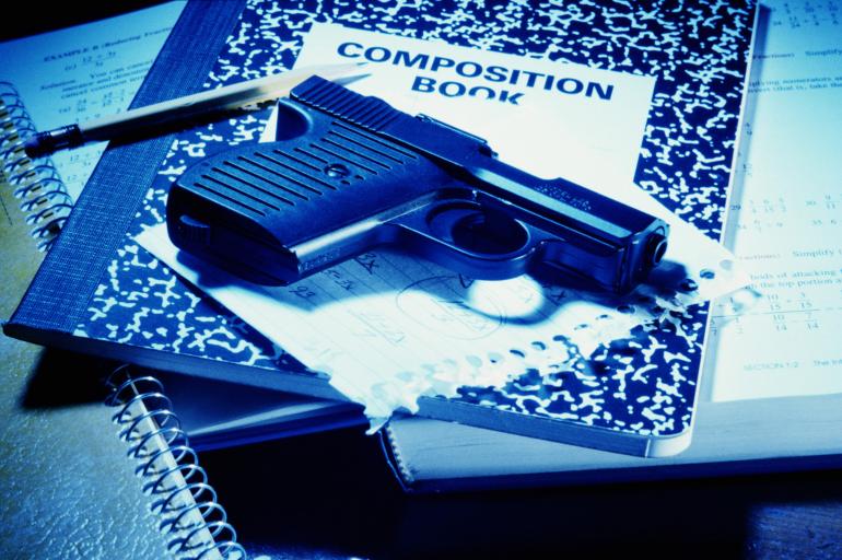 A gun and school supplies. A gun and various school supplies.