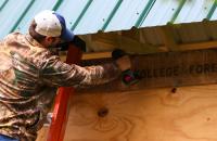 Ethan Carr attaches a sign marking the entrance to the Glenville State College Forest. (GSC Photo/Dustin Crutchfield)
