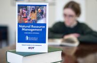 A brochure detailing information about the Glenville State University Natural Resource Management High School Program is featured with a student reading in the background. (GSU Photo/Kristen Cosner)