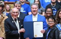 Glenville State University President Dr. Mark Manchin (center with folder) is flanked by Speaker Roger Hanshaw, Ike Morris, Glenville State’s Pioneer Mascot Noah Schultz, and other students, faculty, and staff during a Glenville State University Day recognition inside the West Virginia House of Delegates chamber. (WV Legislative Photography Photo/Perry Bennett)