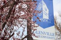 A Glenville State University banner hangs on campus among spring blooms. (GSU Photo/Seth Stover)