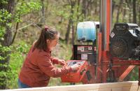 Glenville State College student Gabrielle Dean cuts a log down into boards using the College’s portable Wood-Mizer bandsaw. (GSC Photo/Kristen Cosner)