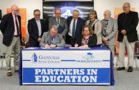 Glenville State College President Dr. Tracy Pellett (seated, left) and Nicholas County Schools Superintendent Dr. Donna Burge-Tetrick (seated, right) sign an agreement backed by GSC representatives, Nicholas County Board of Education members, and Nicholas County and Richwood High School principals