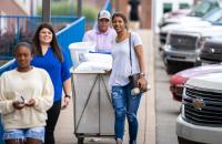 A family wheels a cart of items down the sidewalk in front of Goodwin Hall at Glenville State University as a new student prepares to move in on Monday, August 8. (GSU Photo/Kristen Cosner)