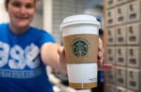 Glenville State University coffee shop employee Caroline Tinnel holds out a We Proudly Serve Starbucks cup. (GSU Photo/Kristen Cosner)