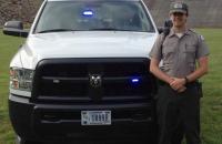 Michael Pracht stands at his patrol vehicle with the Burnsville Dam in the background