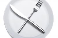 A plate with a fork and knife crossed over top of it.